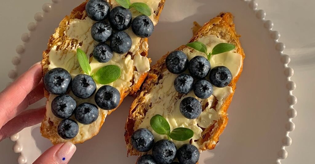 Delicious blueberry and butter toast on a plate held by a person, perfect for breakfast inspiration.